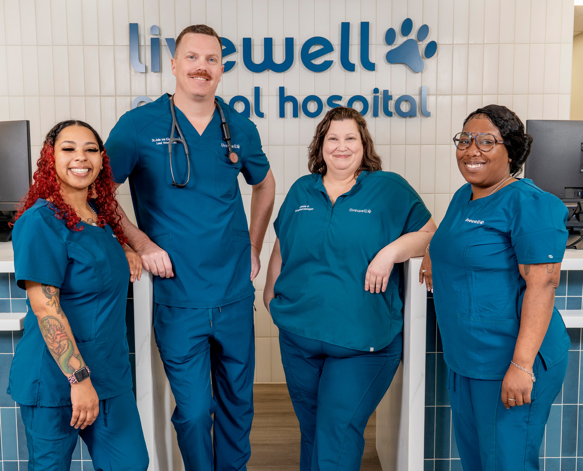 Hospital staff photo in scrubs in front of desk.